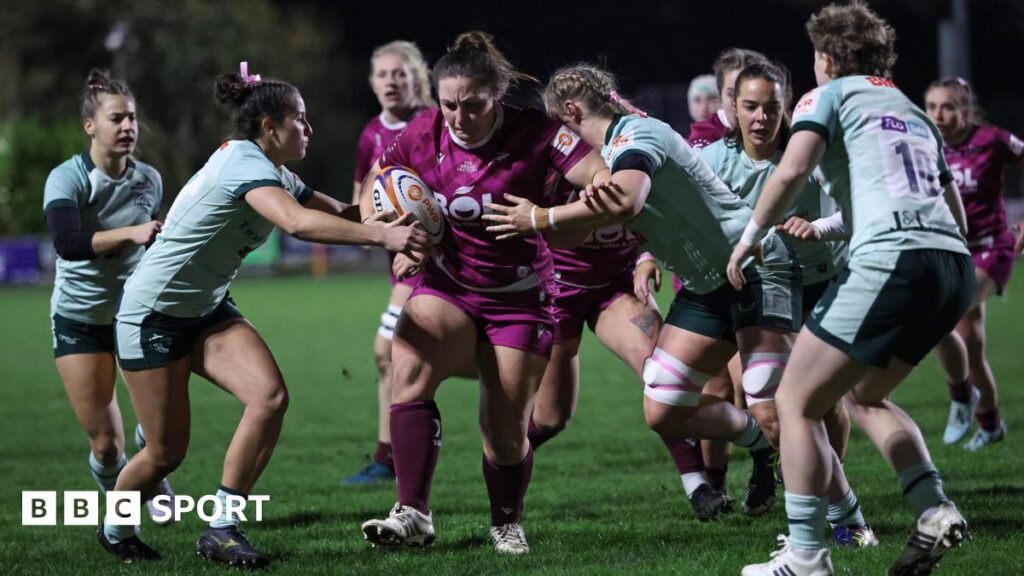 Leicester Tigers Women ‘deserve’ fresh club backing Exeter Chiefs Women rugby football union player Maddie Feaunati holds the ball while holding past a Leicester Tigers Women player during a Women's Premiership Rugby match on grass. Feaunati is wearing a predominantly black kit with white lettering, while her opponent is wearing a light green shirt with dark green trim and dark green shorts. Both players are wearing white boots