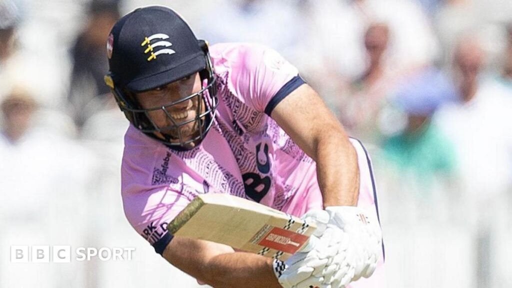 T20 Blast: Middlesex beat Sussex for first win in 2026 competition Josh de Caires batting for Middlesex holding his bat out in front of him wearing a pink shirt and helmet