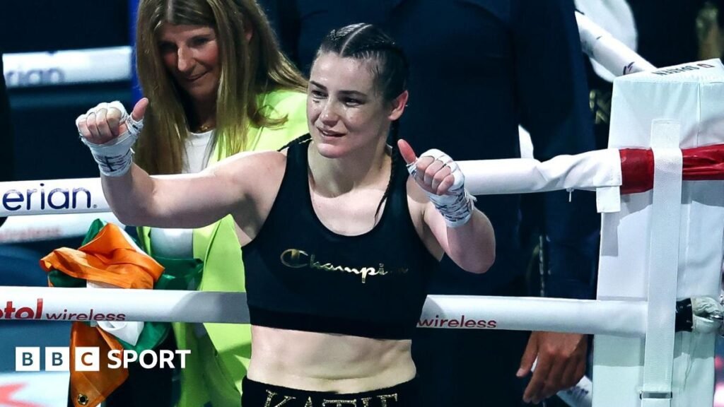 Katie Taylor holds up her thumbs as she stands in a boxing ring