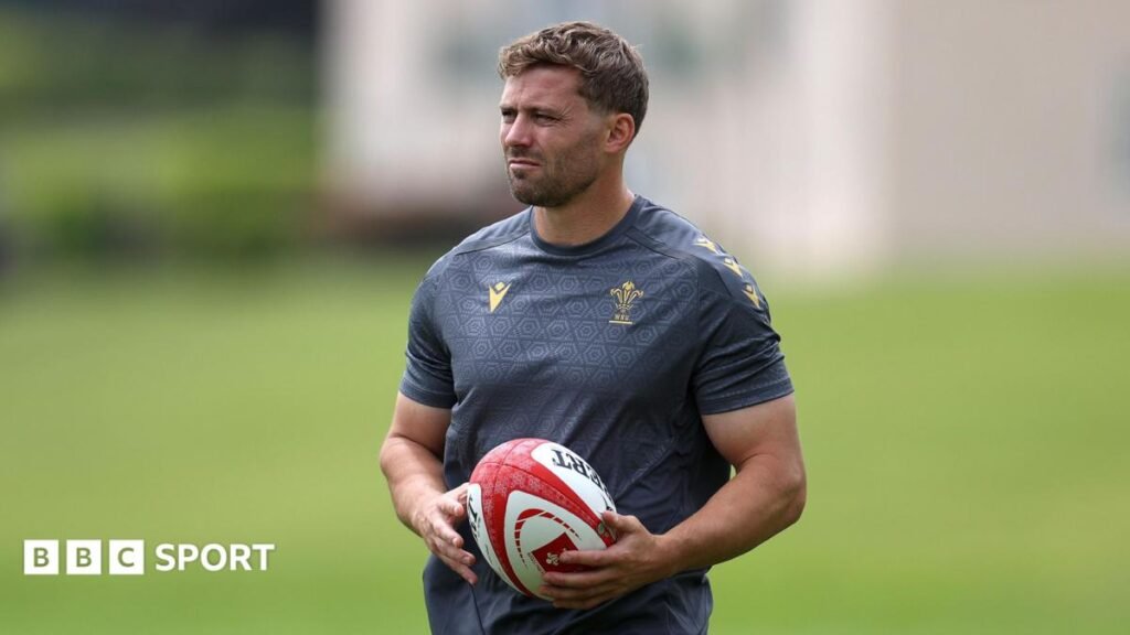 Leigh Halfpenny holds a ball while watching Wales training