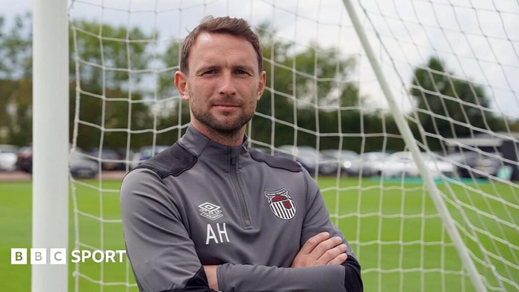 Mark Hughes ‘totally heartbroken’ after death of son Alex, 38 Alex Hughes posing for a picture while stood in a goal wearing a Grimsby Town tracksuit