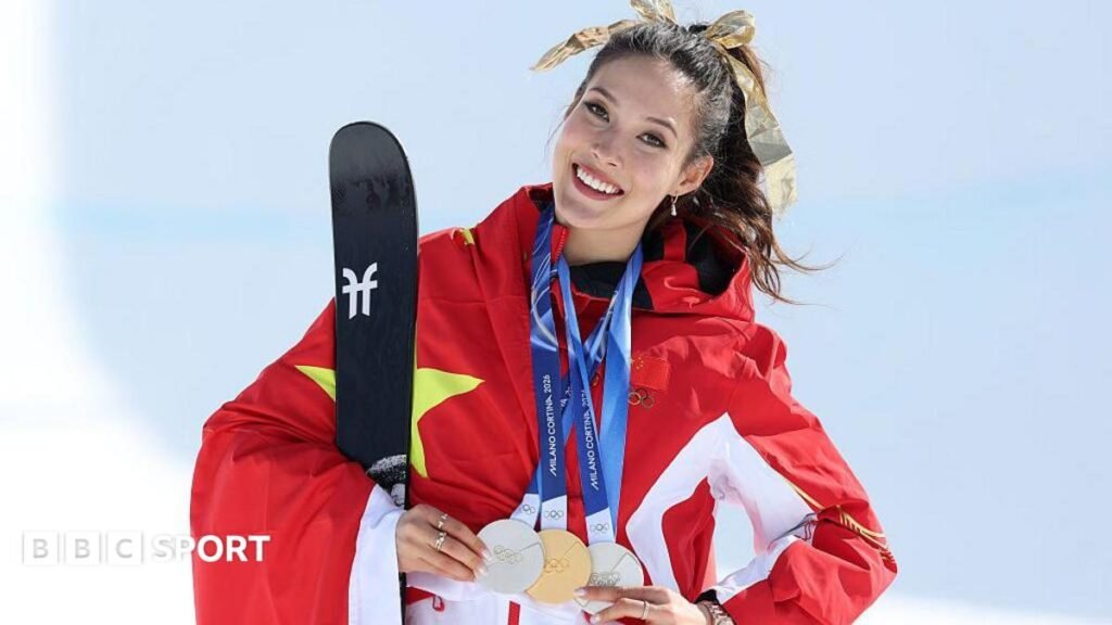 Eileen Gu poses while holding her three medals from the Milano Cortina 2026 Winter Olympics