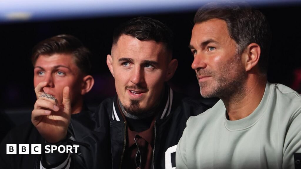 Eddie Hearn and Tom Aspinall talk while they watch a boxing match in April 2026