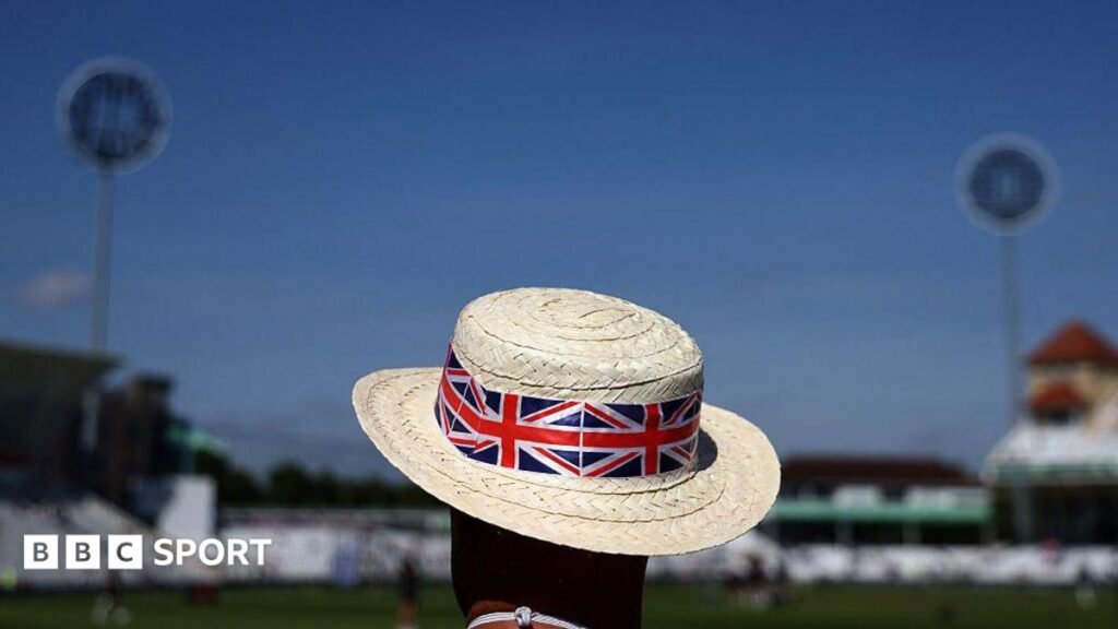 A man wearing a sun hat adorned with a Union Jack design watches on before a cricket match at Trent Bridge in Nottingham