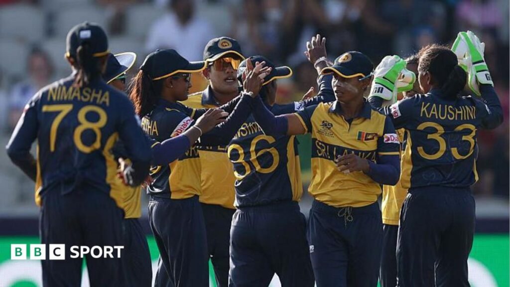 Sri Lanka's players, wearing dark blue and yellow shirts and blue trousers, exchange high fives to celebrate a wicket