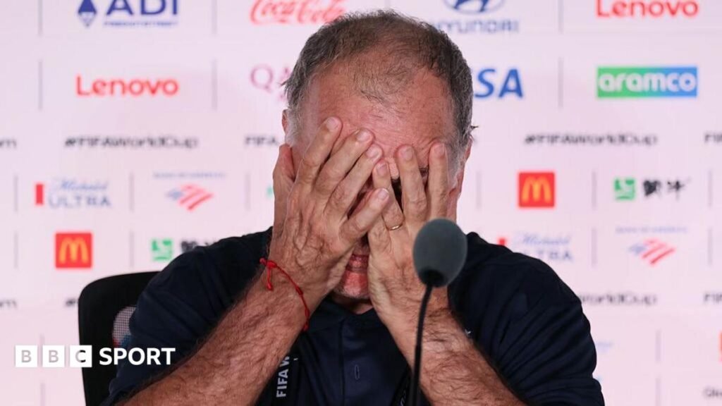 Marcelo Bielsa holds his head in his hands during a media conference after Uruguay's 1-0 defeat by Spain