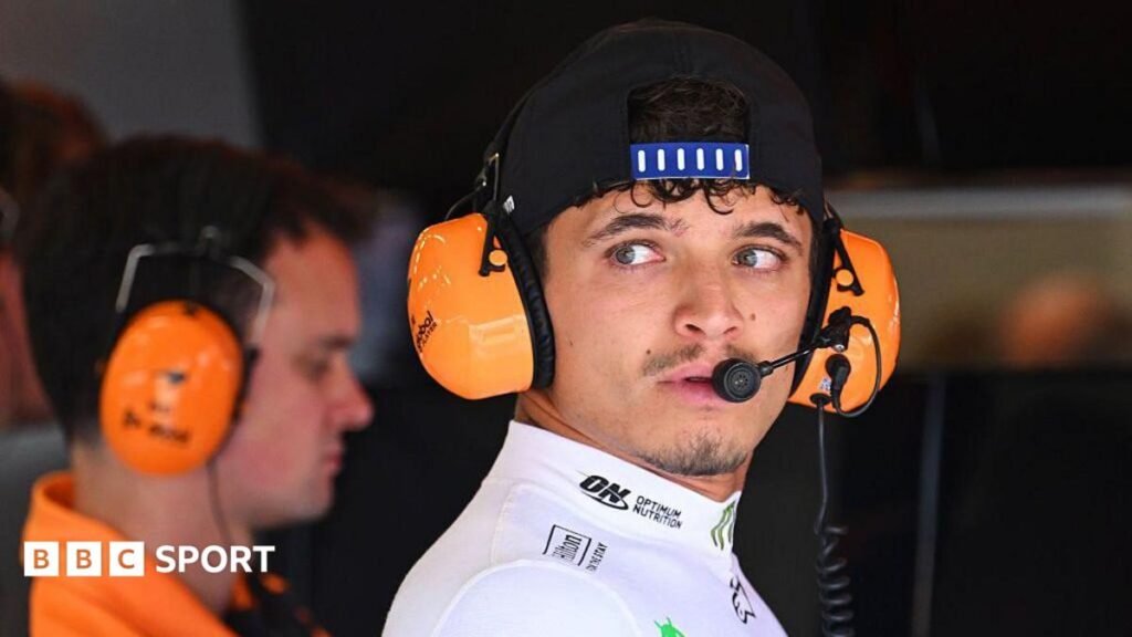 Lando Norris wears headphones in the McLaren garage