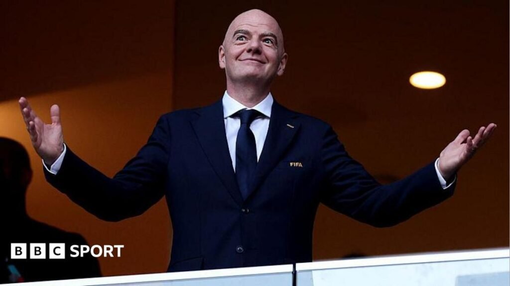 Gianni Infantino opens door to 64-team World Cup Gianni Infantino holds his arms out at each side with open palms, as he smiles while wearing a buttoned-up, dark smart jacket with FIFA written on its breast pocket