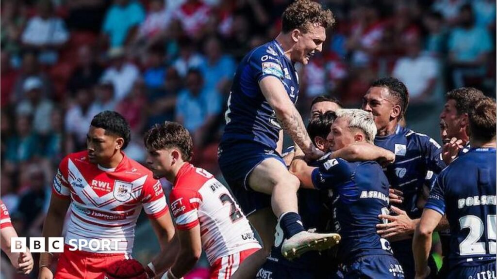 Toulouse players, in dark blue, celebrate a try against St Helens, two of whose players, in red and white, look disconsolate.
