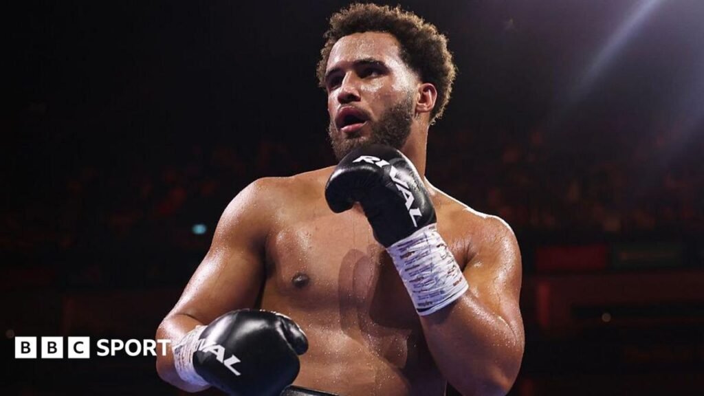 Moses Itauma holds up his hands and is wearing black boxing gloves