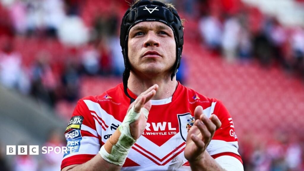 Jonny Lomax, wearing a trademark scrum cap with the chin strap undone, applauds the St Helens fans after a match