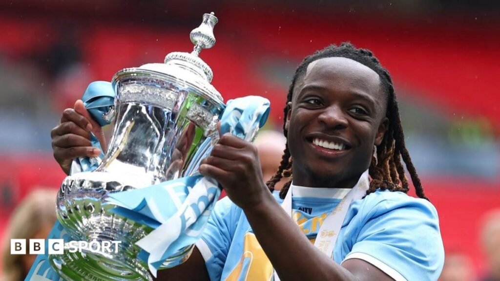 Manchester City Jeremy Doku smiles as he holds the FA Cup