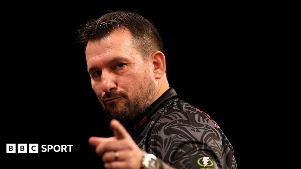 Jonny Clayton points with the index finger of his left hand as he celebrates at a Premier League darts event