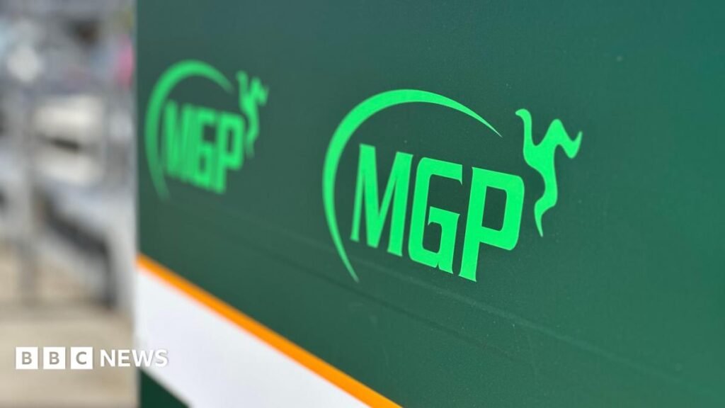 A large green sign with the MGP logo on it in pitlane.