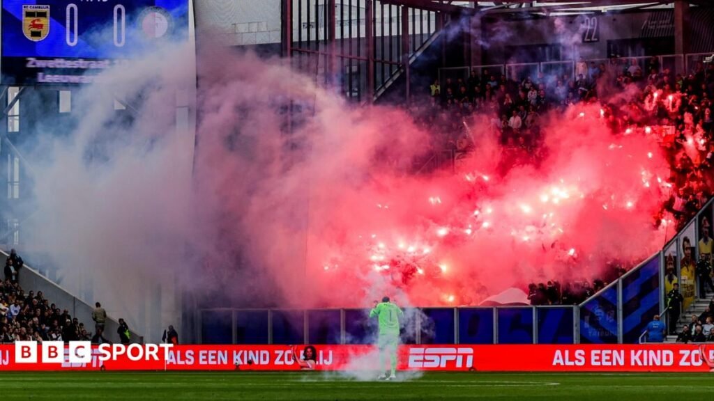Feyenoord supporters set off fireworks and throw them onto the pitch near goalkeeper Tjark Ernst during their match at SC Cambuur