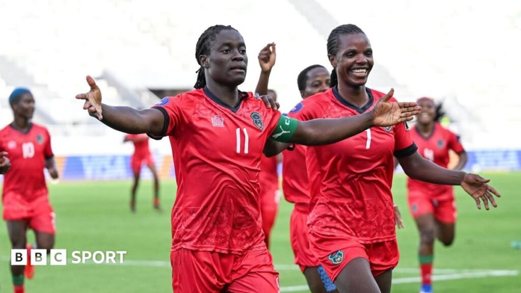 Wafcon 2026: Algeria 1-3 Malawi – Chawinga sisters fire Scorchers into final Malawi striker Tabitha Chawinga runs towards the touchline with arms spread wide to either side of her body to celebrate a goal at the 2026 Women's Africa Cup of Nations in Morocco. She wears all-red kit with green and black trim and is surrounded by a number of smiling team-mates who are running in her wake across the lush green pitch