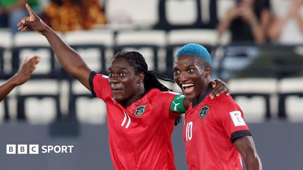 Wafcon 2026: Tabitha and Temwa Chawinga lead Malawi bid for glory in final Tabitha Chawinga raises her right arm in celebration and puts her left arm around the shoulder of Temwa Chawinga, who has dyed blue hair and a wide-mouthed smile on her face. Both players wear red Malawi shirts with black trim - Tabitha with a green captain's armband and a white number 11 on the front and Temwa with a number 10 on the chest. The pair are visible from stomatch up and a sparsely-populated stand can be seen out of focus in the background