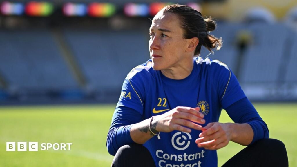 Lucy Bronze in Chelsea kit sitting down on a football pitch