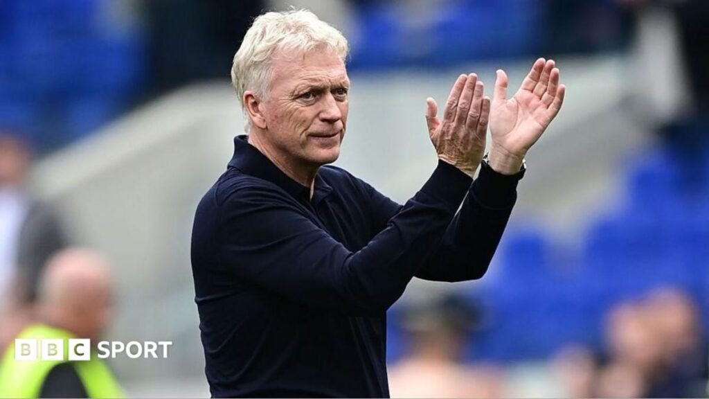 David Moyes, in a long-sleeved dark shirt, stands and applauds