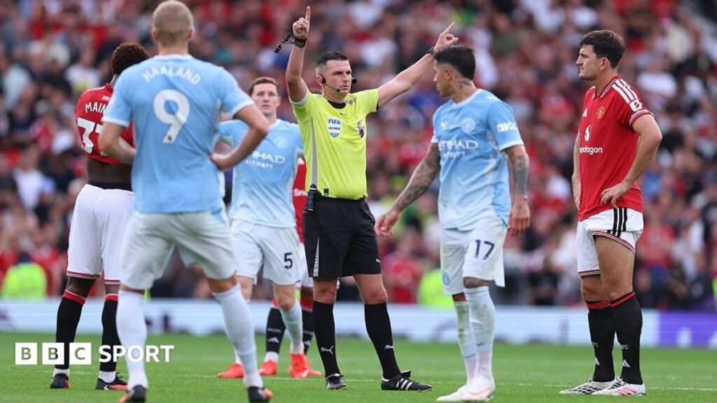 Players wait for referee Michael Oliver to reveal the VAR decision for the goal scored by Erling Haaland for Manchester City against Manchester United