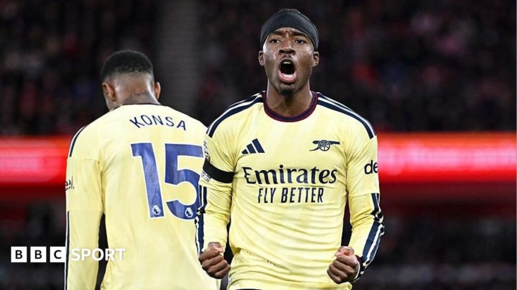 Noni Madueke, in Arsenal's yellow kit, celebrates with clenched fists