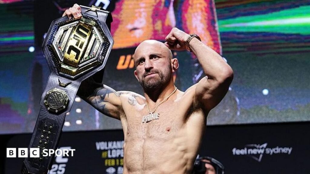 Alexander Volkanovski raises his UFC featherweight title after a news conference